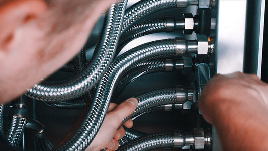 Close-up of hands working with metallic hoses and connectors.