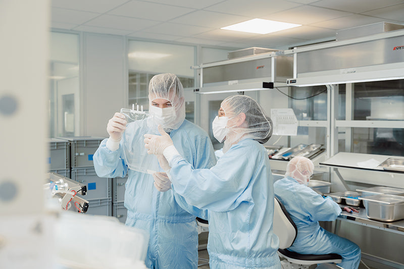 Cleanroom production workers assembling single-use bags and assemblies for bioprocessing applications.