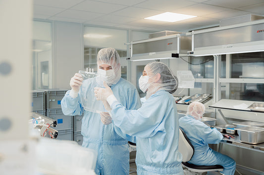 Cleanroom production workers assembling single-use bags and assemblies for bioprocessing applications.