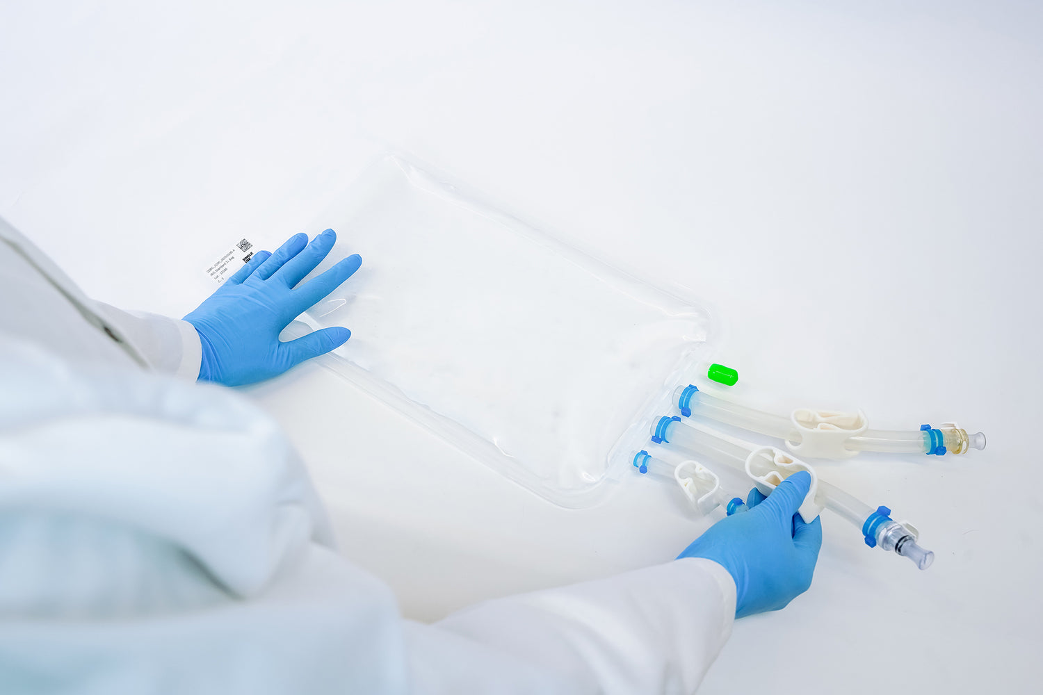 A 2l IRIS single-use bag, held by a person wearing blue gloves.