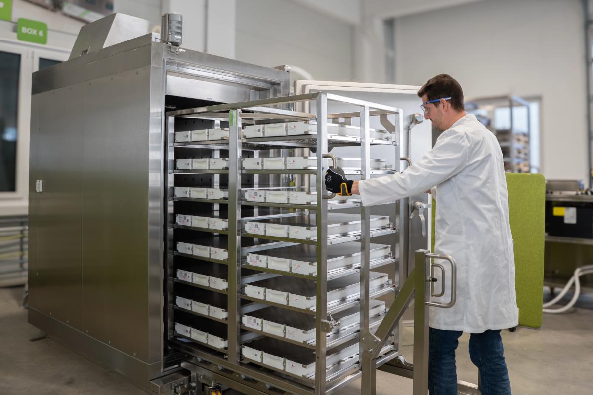 Manufacturing operator working with a large industrial blast freezer with a batch of drug substance.