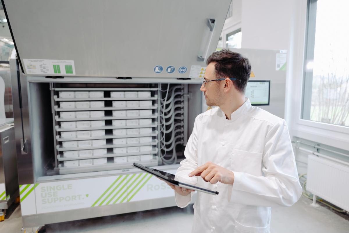 Operator in front of plate-based freezer for mRNA in single-use bags, using ipad.