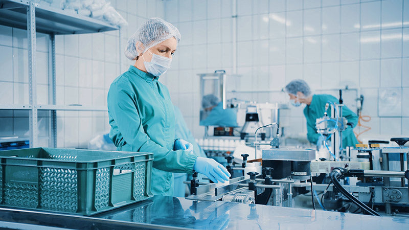 Technician operating pharmaceutical manufacturing machinery in CDMO facility.