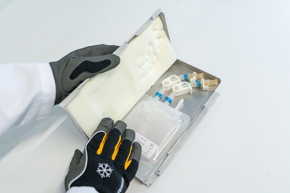 Top-down view of an open RoSS.KSET containing a small single-use bag, with a hand holding it.