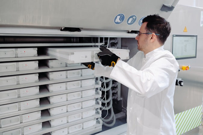 Operator loading a plate freezer with biologics in single-use bags protected by the RoSS shell