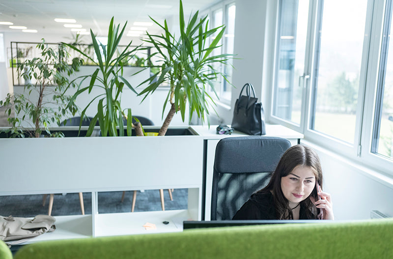 A Single Use Support team member sitting at a desk in the Kufstein office, with plants in the background.